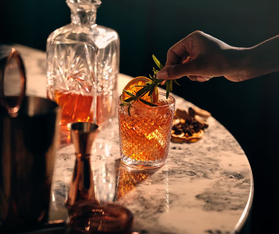 Adding a garnish to a finished cocktail with a cocktail kit on a marble table