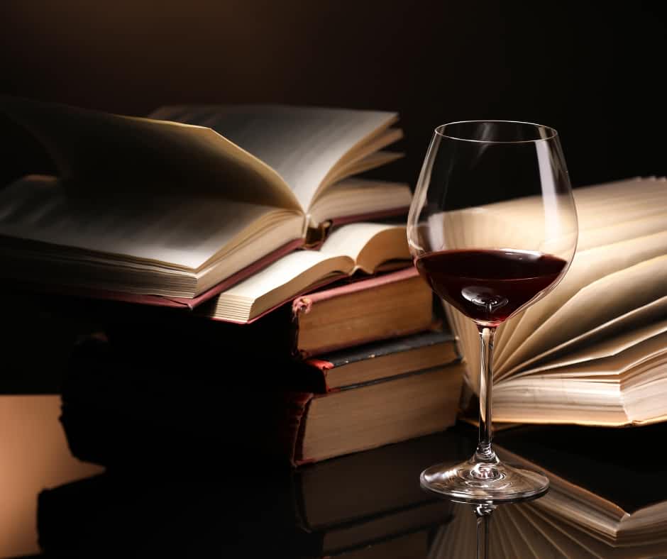 A glass of red wine placed in front of a stack of books