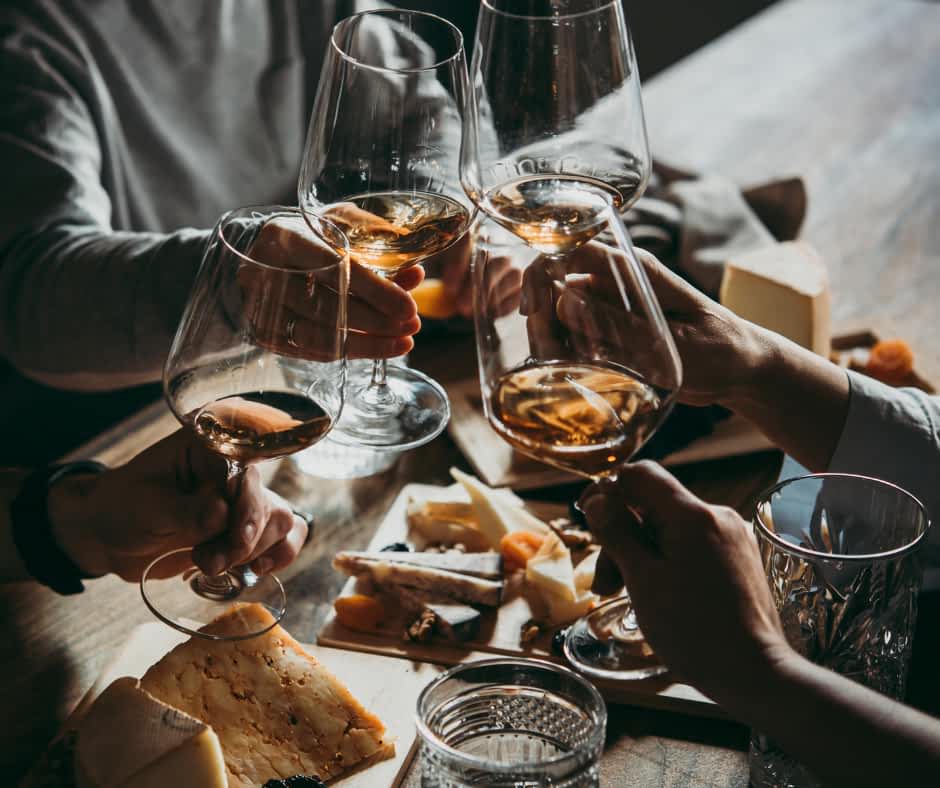 A group of friends clinking wine glasses with a cheese board in the background