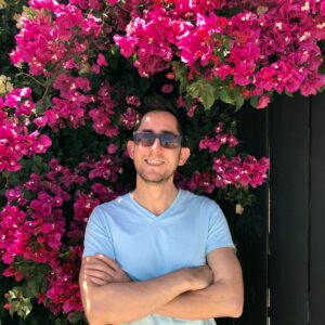 Marco from Travel Boo posting next to a bougainvillea tree